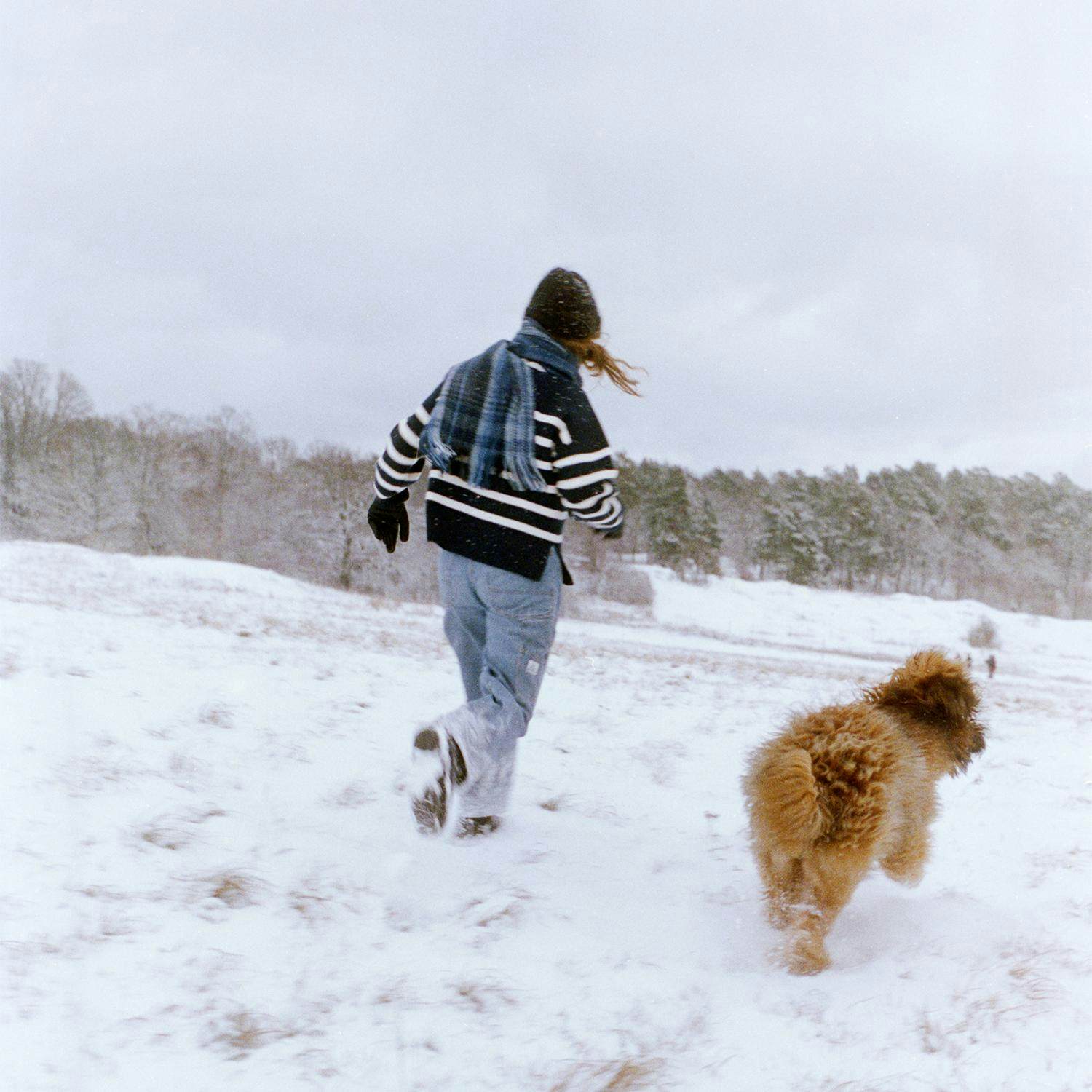 Hundägare springer och leker med sin hund utomhus.